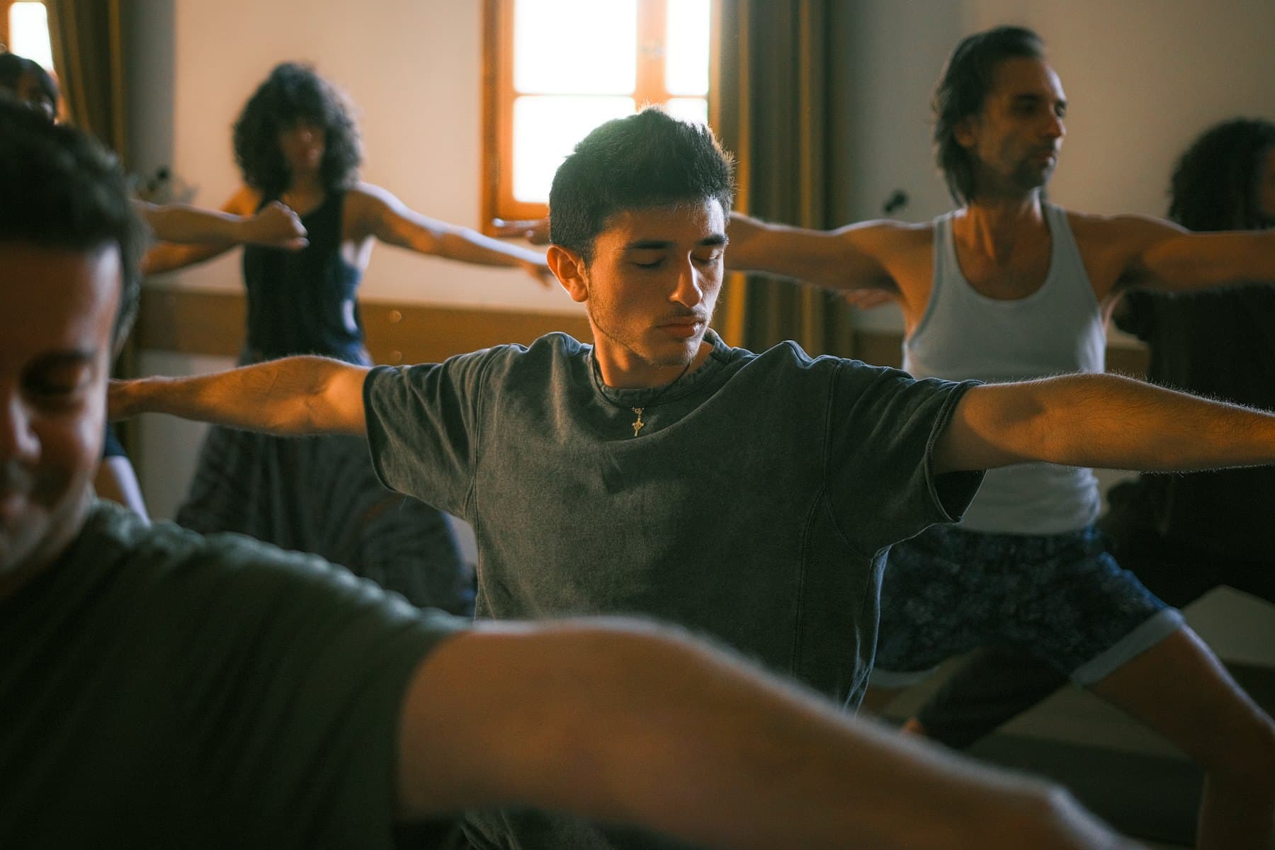 Grupo entrenando con los brazos extendidos en una clase de estudio