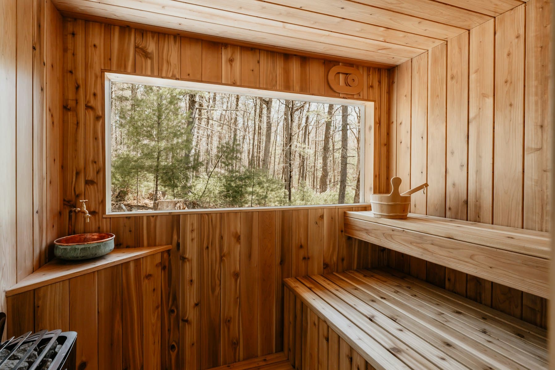 Sauna de madera con ventanal hacia un bosque