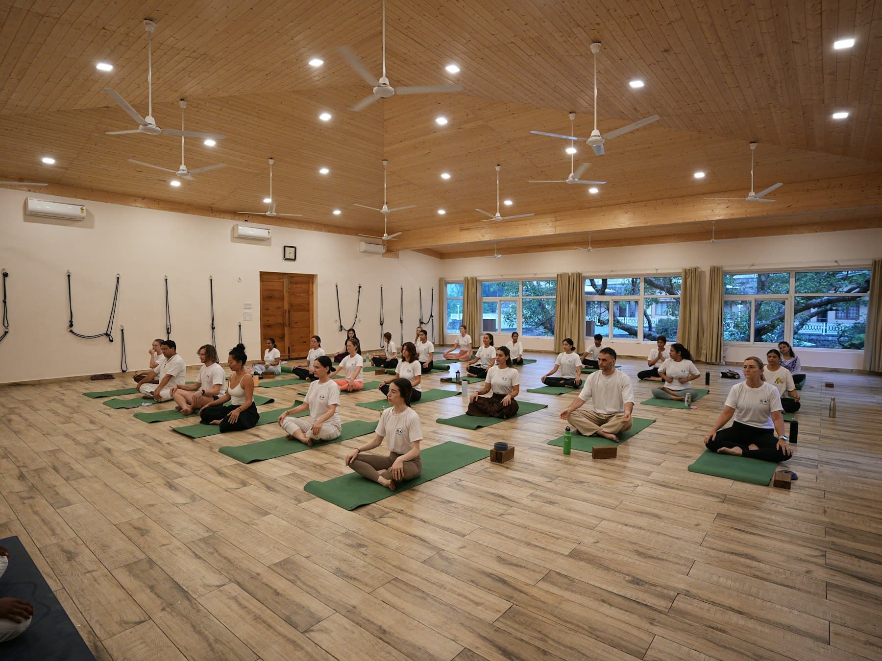 Clase grupal de yoga en un estudio amplio con piso de madera